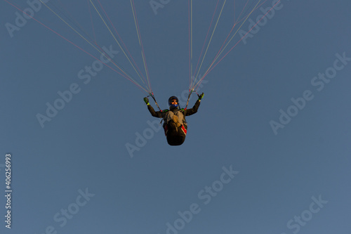 A beautiful view of a paraglide flying gliding on a clear blue sky at the golden hour with a nice wind windy breeze on a sunny day 