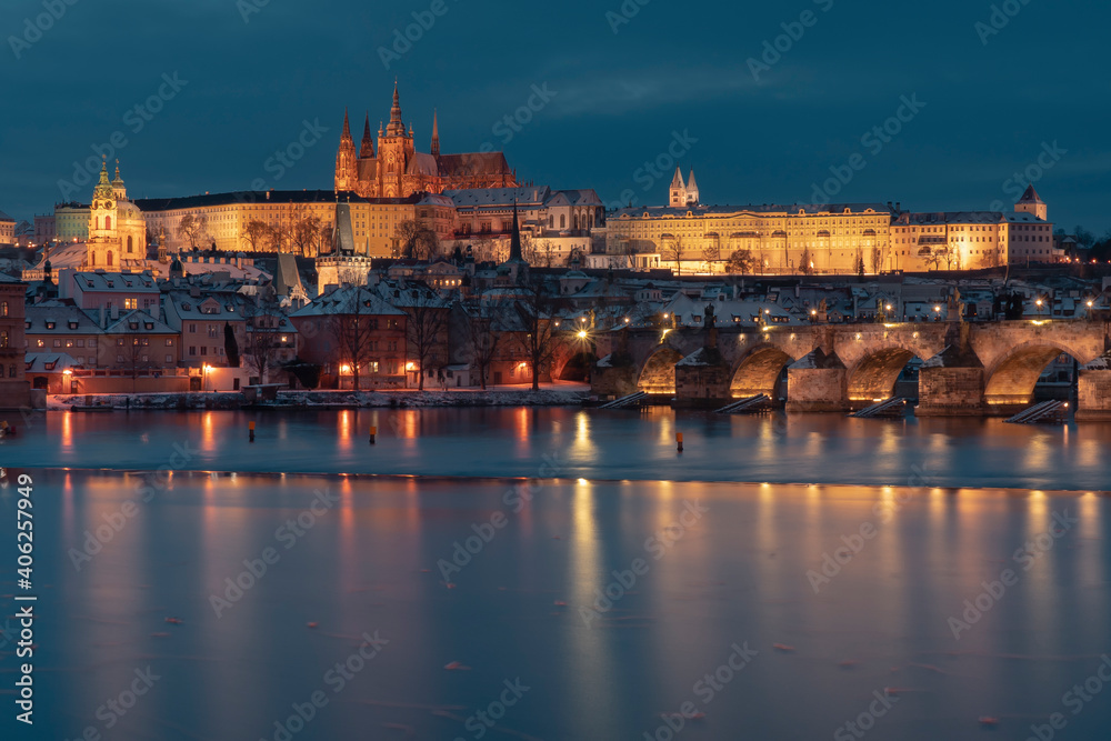 .Charles Bridge on the Vltava River and Prague Castle and the Church of St. Vitus in winter and snow on the roofs in the center of Prague in the early evening