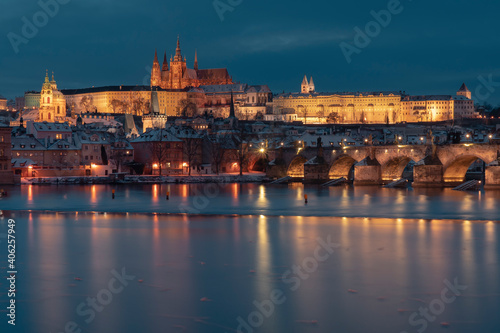 .Charles Bridge on the Vltava River and Prague Castle and the Church of St. Vitus in winter and snow on the roofs in the center of Prague in the early evening
