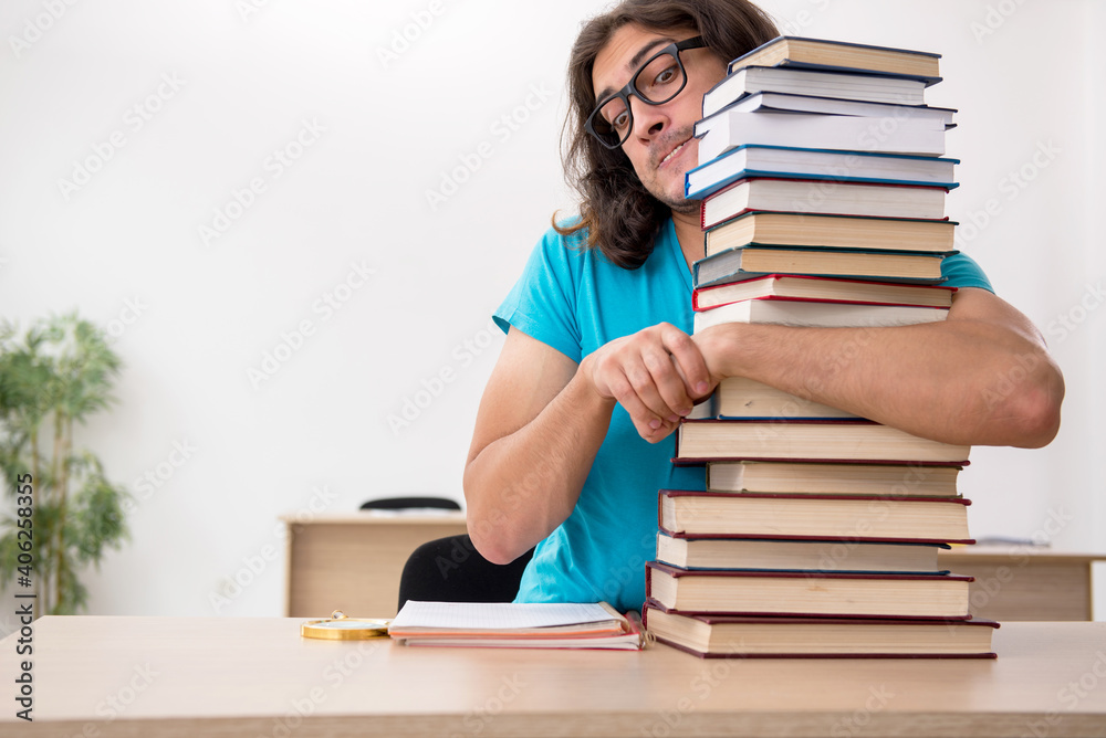 Young male student and a lot of books in the class Young male student and a lot of books in the class