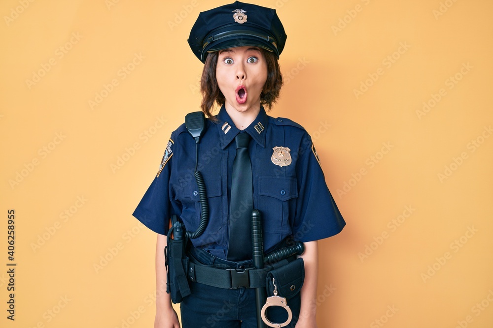 Young beautiful woman wearing police uniform afraid and shocked with surprise expression, fear and excited face.