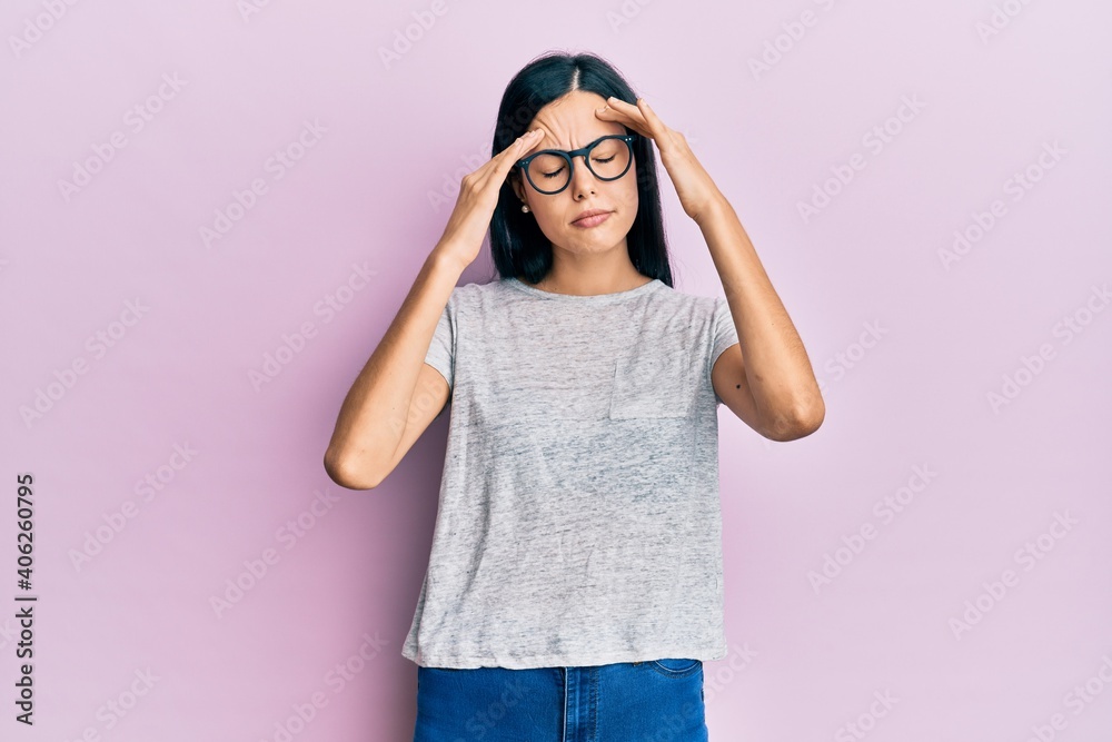 Beautiful young woman wearing casual clothes and glasses with hand on head, headache because stress. suffering migraine. Beautiful young woman wearing casual clothes and glasses with hand on head, headache because stress. suffering migraine.