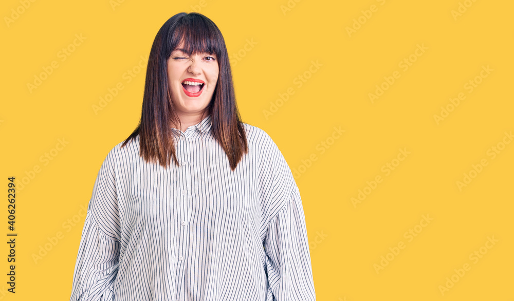 Young plus size woman wearing casual clothes winking looking at the camera with sexy expression, cheerful and happy face.