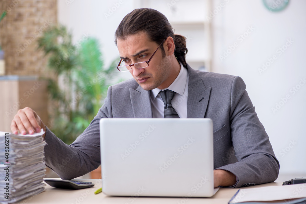 Young male employee unhappy with excessive work in the office Young male employee unhappy with excessive work in the office