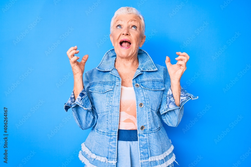Obraz premium Senior beautiful woman with blue eyes and grey hair wearing casual denim style crazy and mad shouting and yelling with aggressive expression and arms raised. frustration concept.