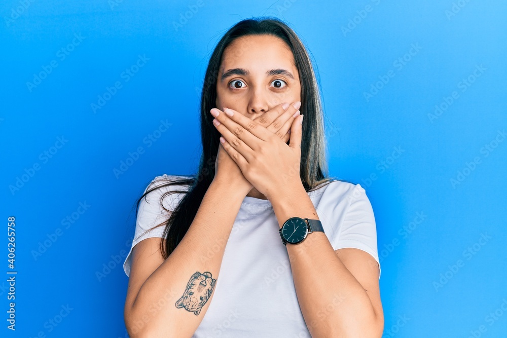 Young hispanic woman wearing casual white t shirt shocked covering mouth with hands for mistake. secret concept. Young hispanic woman wearing casual white t shirt shocked covering mouth with hands for mistake. secret concept.