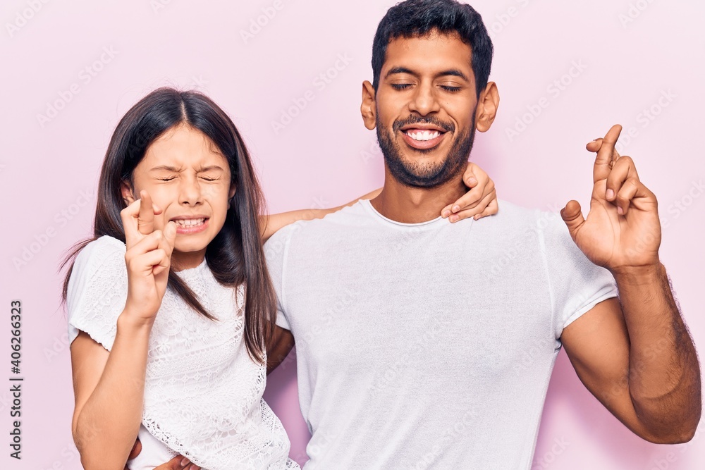 Young father and daughter wearing casual clothes gesturing finger crossed smiling with hope and eyes closed. luck and superstitious concept. Young father and daughter wearing casual clothes gesturing finger crossed smiling with hope and eyes closed. luck and superstitious concept.