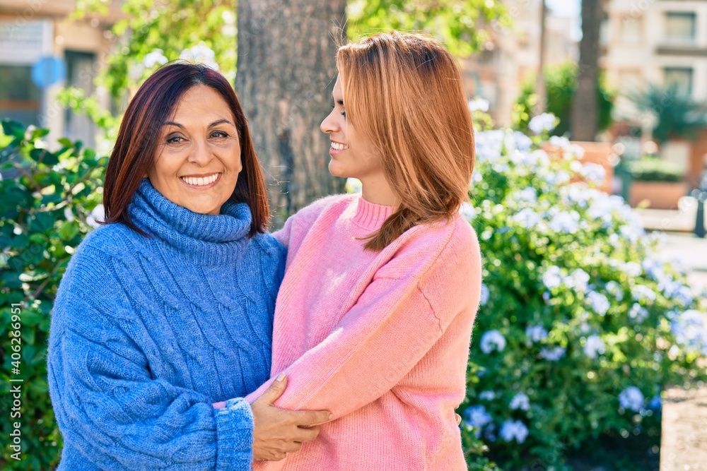 Hispanic mother and daughter smiling happy and hugging at the park. Hispanic mother and daughter smiling happy and hugging at the park.