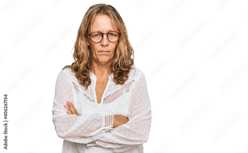 Middle age blonde woman wearing casual white shirt and glasses skeptic and nervous, disapproving expression on face with crossed arms. negative person. Middle age blonde woman wearing casual white shirt and glasses skeptic and nervous, disapproving expression on face with crossed arms. negative person.