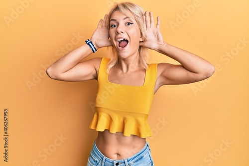 Young blonde girl wearing casual clothes smiling cheerful playing peek a boo with hands showing face. surprised and exited © Krakenimages.com