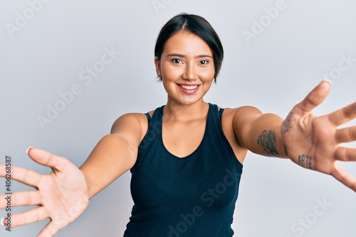 Beautiful young woman with short hair wearing casual clothes looking at the camera smiling with open arms for hug. cheerful expression embracing happiness.