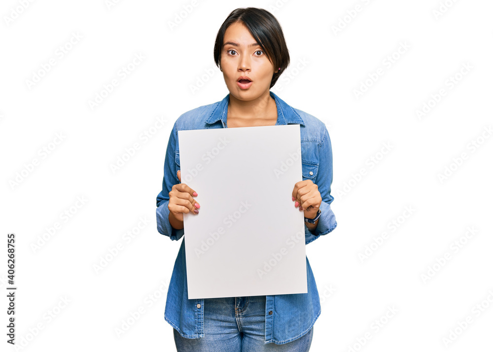 Beautiful young woman with short hair holding blank empty banner scared and amazed with open mouth for surprise, disbelief face Beautiful young woman with short hair holding blank empty banner scared and amazed with open mouth for surprise, disbelief face