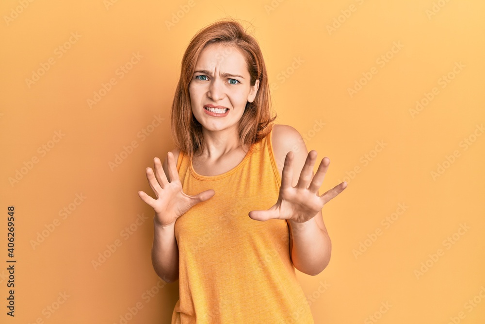 Young caucasian woman wearing casual style with sleeveless shirt disgusted expression, displeased and fearful doing disgust face because aversion reaction. with hands raised Young caucasian woman wearing casual style with sleeveless shirt disgusted expression, displeased and fearful doing disgust face because aversion reaction. with hands raised