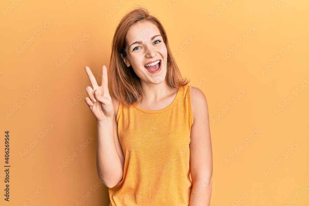 Fototapeta premium Young caucasian woman wearing casual style with sleeveless shirt showing and pointing up with fingers number two while smiling confident and happy.
