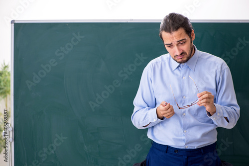 Young underpaid male teacher in the classroom photo