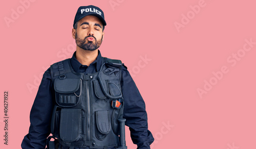 Young hispanic man wearing police uniform looking at the camera blowing a kiss on air being lovely and sexy. love expression.