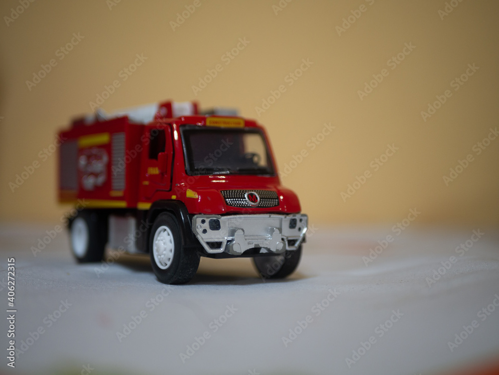 Zabawkowy wóz strażacki czerwony na żółtym tle - obrazy, fototapety, plakaty 