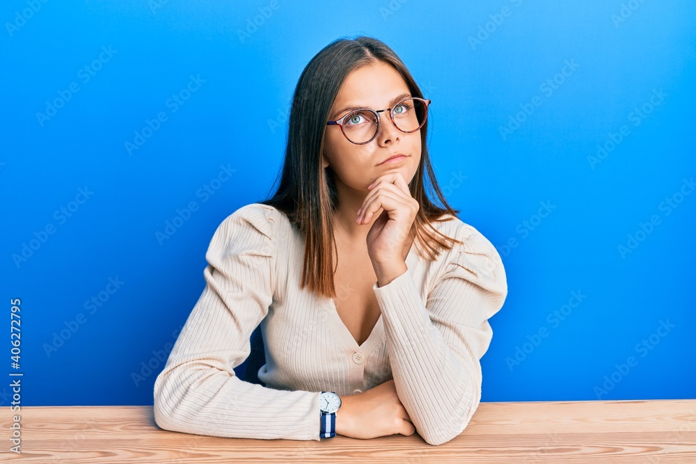 Young caucasian woman wearing casual clothes and glasses thinking concentrated about doubt with finger on chin and looking up wondering Young caucasian woman wearing casual clothes and glasses thinking concentrated about doubt with finger on chin and looking up wondering
