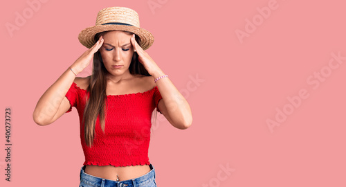 Young beautiful hispanic woman wearing summer hat suffering from headache desperate and stressed because pain and migraine. hands on head. © Krakenimages.com