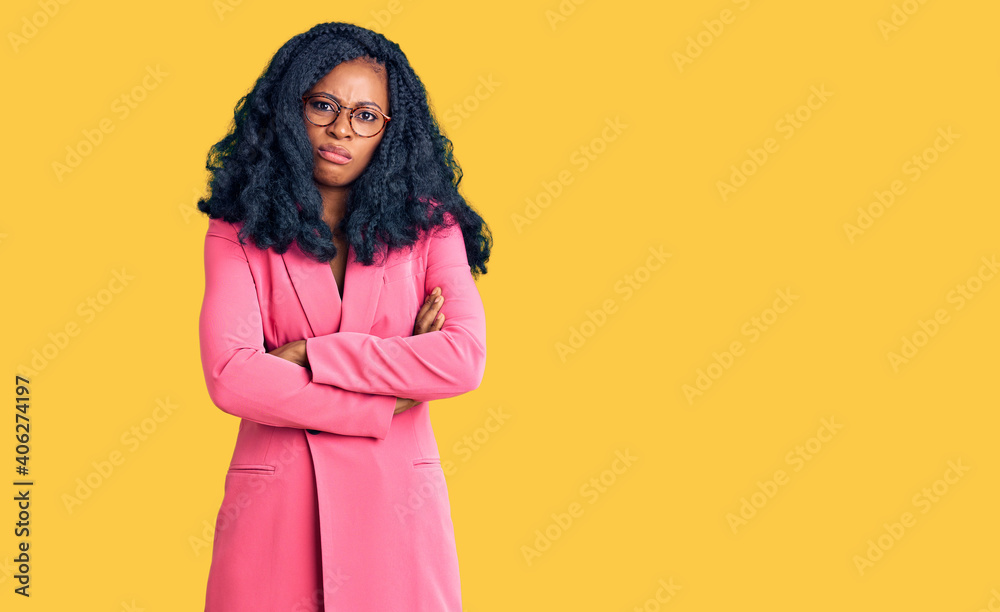 Beautiful african american woman wearing business jacket and glasses skeptic and nervous, disapproving expression on face with crossed arms. negative person. Beautiful african american woman wearing business jacket and glasses skeptic and nervous, disapproving expression on face with crossed arms. negative person.