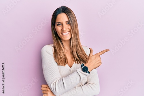 Brunette young woman wearing casual clothes smiling cheerful pointing with hand and finger up to the side © Krakenimages.com