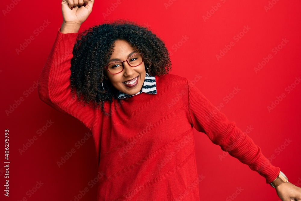 Beautiful african american woman with afro hair wearing sweater and glasses dancing happy and cheerful, smiling moving casual and confident listening to music Beautiful african american woman with afro hair wearing sweater and glasses dancing happy and cheerful, smiling moving casual and confident listening to music