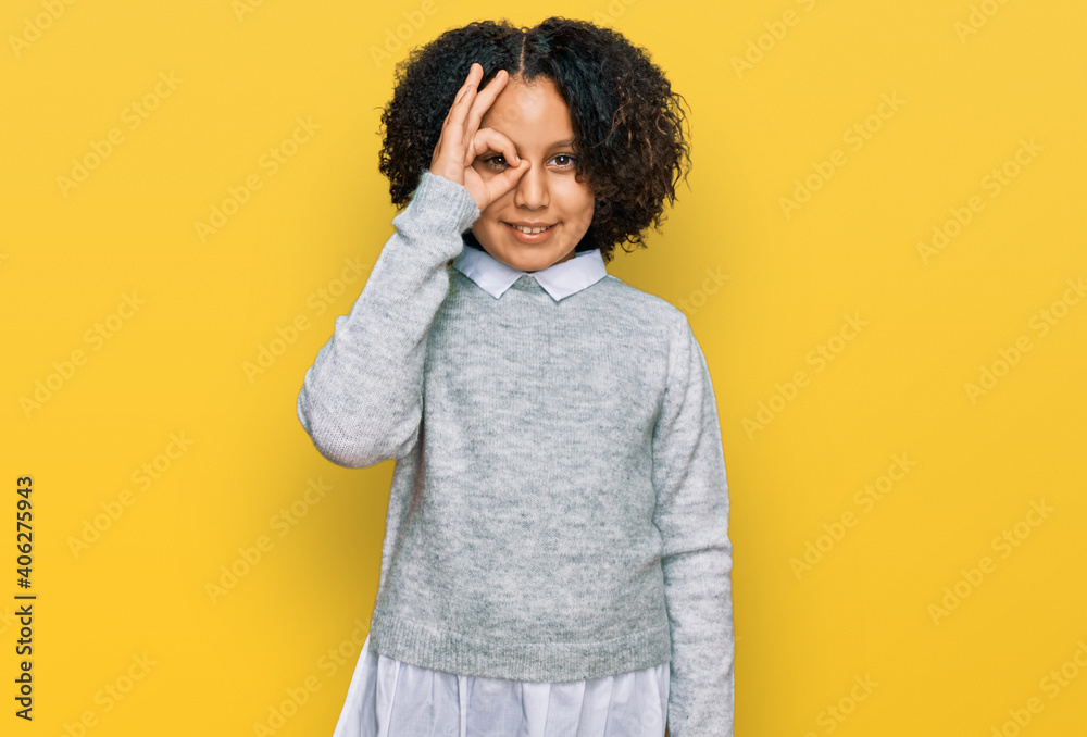 Young little girl with afro hair wearing casual clothes doing ok gesture with hand smiling, eye looking through fingers with happy face. Young little girl with afro hair wearing casual clothes doing ok gesture with hand smiling, eye looking through fingers with happy face.