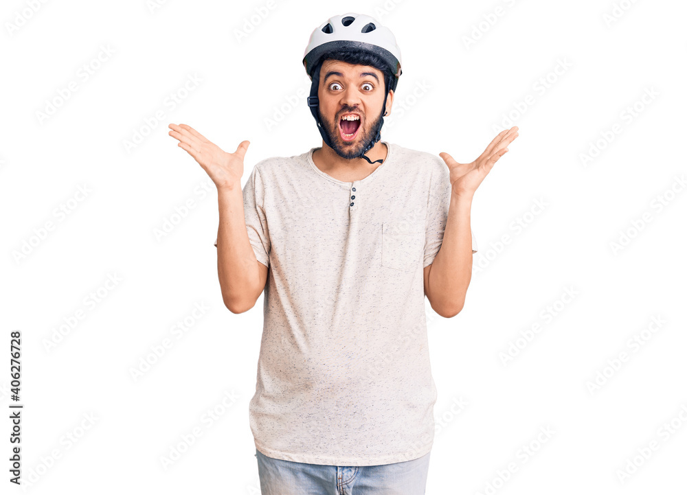 Young hispanic man wearing bike helmet celebrating victory with happy smile and winner expression with raised hands