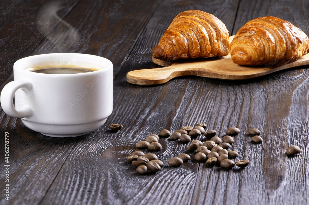 A cup of hot coffee and croissants on a wooden background. Breakfast with coffee and fresh pastry. Copy space. Fresh cake and pastry A cup of hot coffee and croissants on a wooden background. Breakfast with coffee and fresh pastry. Copy space. Fresh cake and pastry