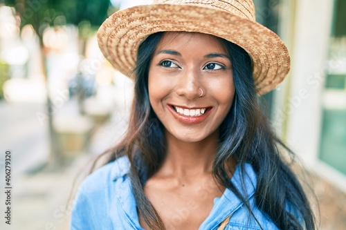 Young beautiful indian woman wearing summer hat smiling happy walking at the city. © Krakenimages.com
