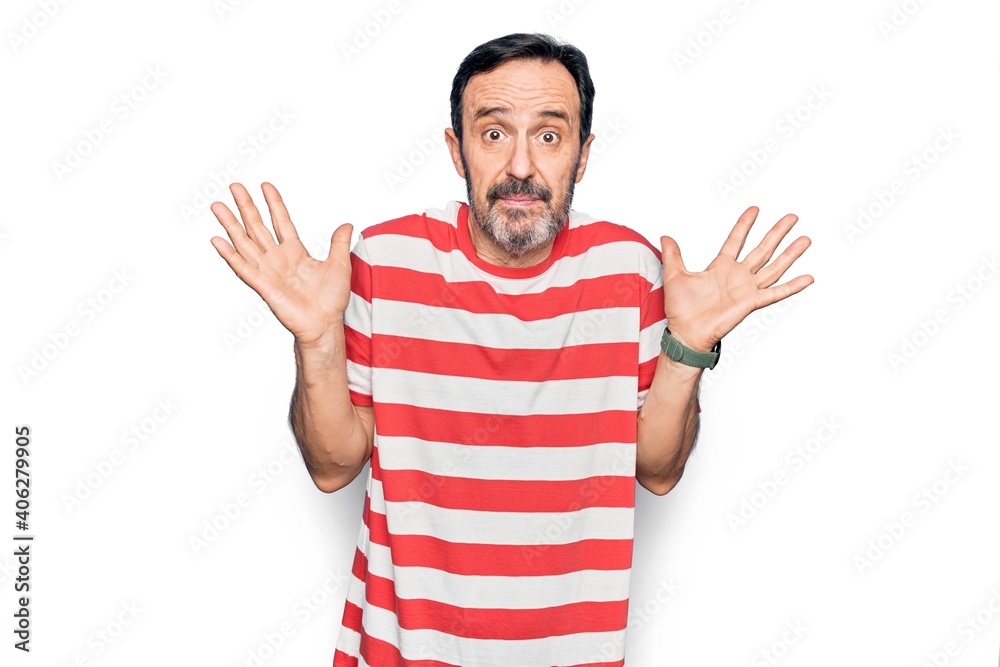 Middle age handsome man wearing striped t-shirt standing over isolated white background clueless and confused with open arms, no idea and doubtful face. Middle age handsome man wearing striped t-shirt standing over isolated white background clueless and confused with open arms, no idea and doubtful face.