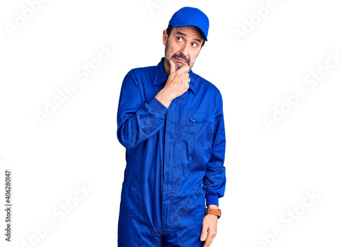 Middle age handsome man wearing mechanic uniform thinking worried about a question  concerned and nervous with hand on chin