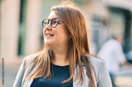 Young hispanic plus size businesswoman smiling happy standing at the city.