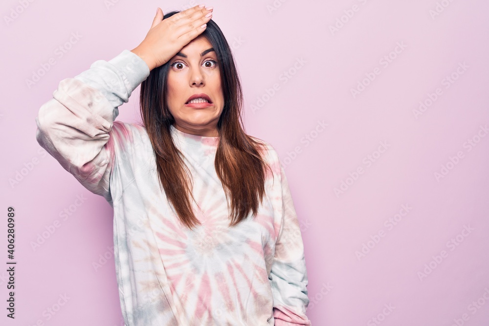 Young beautiful brunette woman wearing casual dyed sweatshirt over isolated pink background surprised with hand on head for mistake, remember error. Forgot, bad memory concept. Young beautiful brunette woman wearing casual dyed sweatshirt over isolated pink background surprised with hand on head for mistake, remember error. Forgot, bad memory concept.