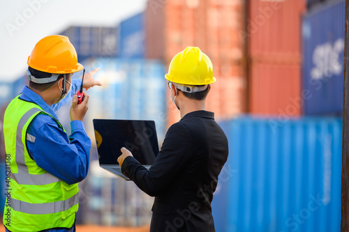 Engineer or Foreman Talk to an Asian businessperson about loading containers from a cargo ship.