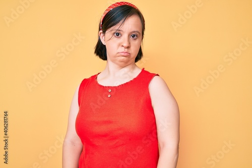 Brunette woman with down syndrome wearing casual clothes with serious expression on face. simple and natural looking at the camera.