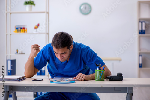 Young male doctor being extremely tired in the clinic