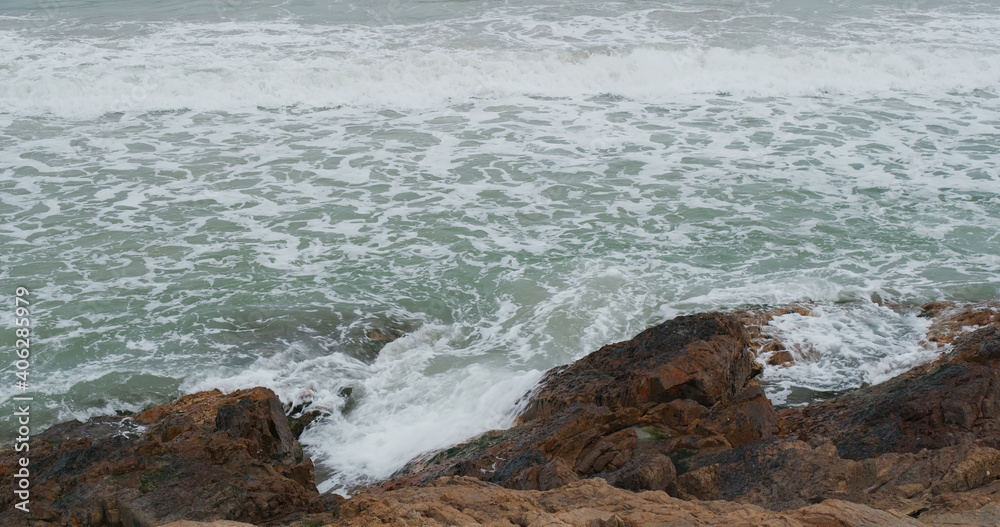 Sea waves splash against rock on island