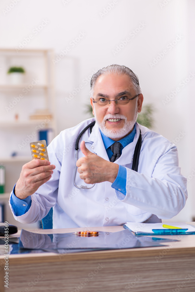 Old male doctor writing prescription in the clinic Old male doctor writing prescription in the clinic