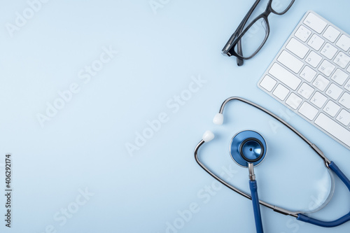 Doctor workplace. Stethoscope and computer keyboard on blue office desk top view copy space