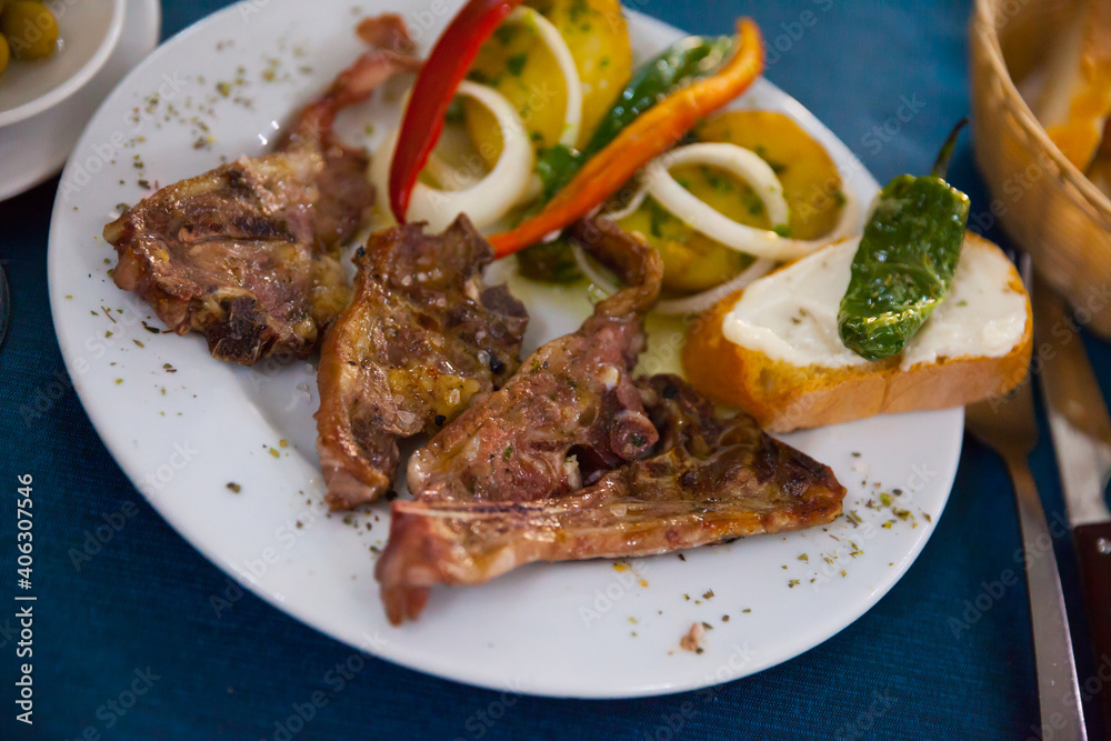 Image of tasty lamb baked and served with bread and vegetables at plate