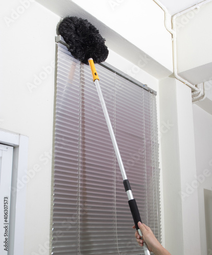 housekeeper cleaning venetian blinds with duster feather