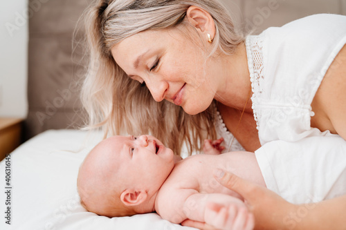 mom is mom is lying down with a baby in a white bed after feeding breast milk. 