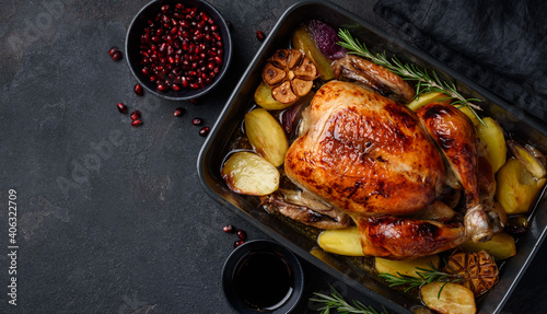 Roasted chicken in pomegranate sauce with potatoes in a gray ceramic mold. Dark background. Top view. Copy space