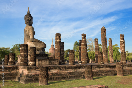Sculpture of a seated Buddha on the ruins of the ancient Buddhist temple Wat Chana Songkhram on a sunny evening. Sukhothai, Thailand