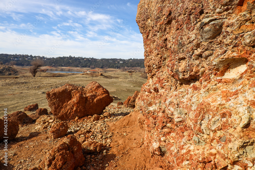 View of Red Conglomerate Rock with Forested Hill and Houses in the Background from Rattlesnake Bar in Newcastle California