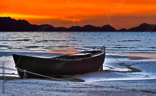 Old wooden fishing boat at sandy tropical beach at dawn