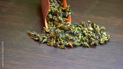 chinese oolong  tea te guan yin close up with wooden spoon on brown background photo