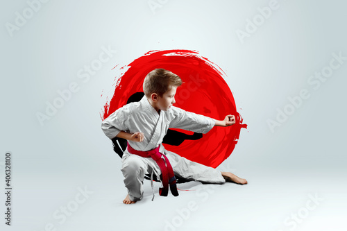Full-length portrait of a boy in a white kimono with a red belt against the background of a red circle. Karate concept, training, goal, training, achievement.