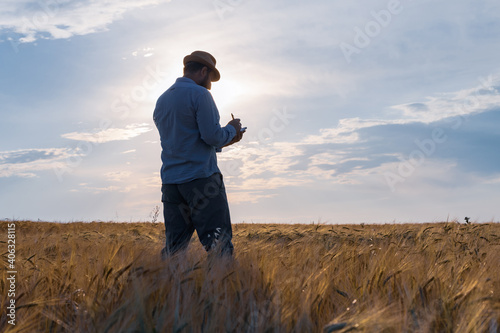 a man farmer in a hat stands on the field and keeps a record of planning work for the day